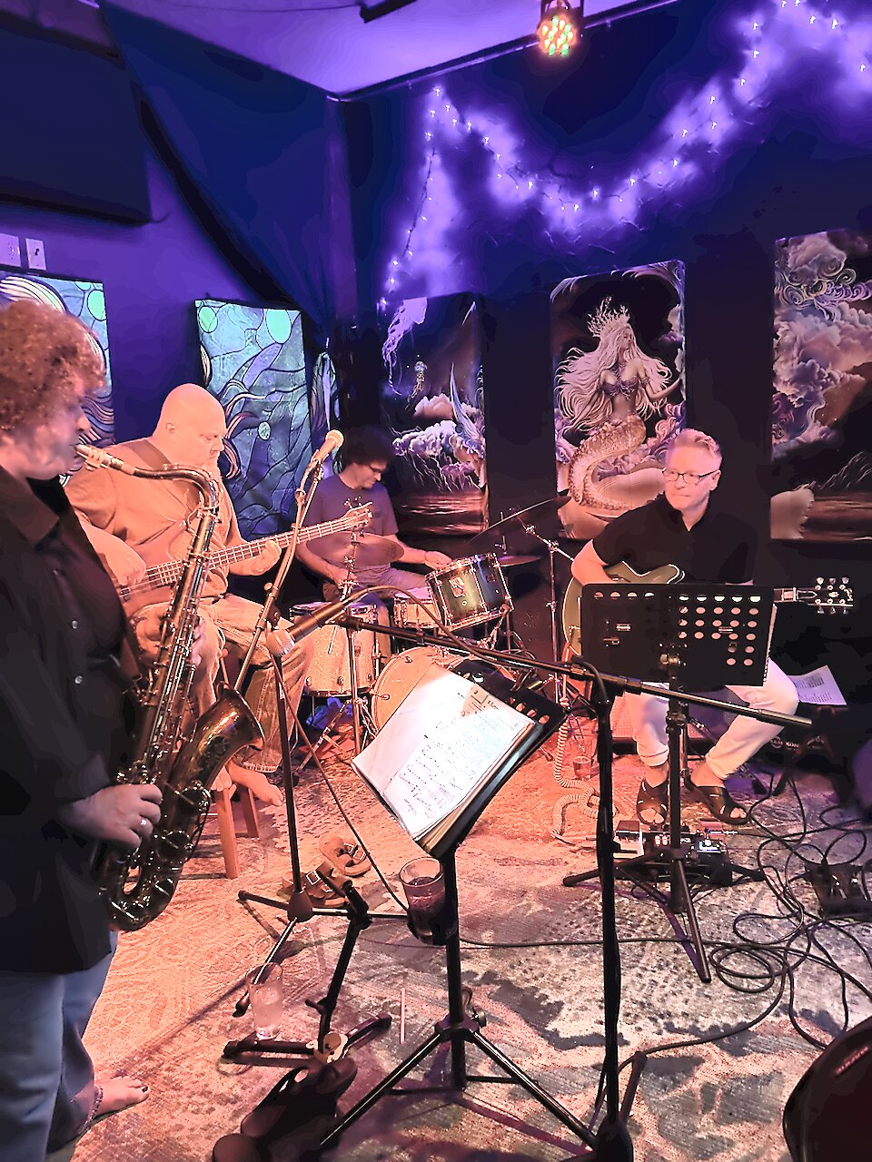 The band on stage under red and blue lights, saxophone in front